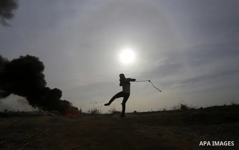 A Palestinian protester uses a sling shot to throw stones during clashes with Israeli security forces near the border between Israeli and central Gaza Strip, on October 23, 2015. Palestinian factions called for mass rall...