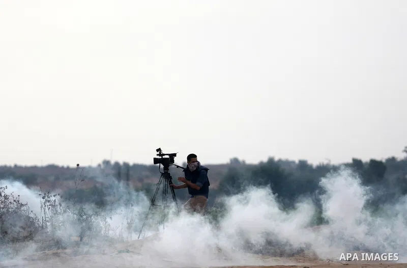 A Palestinian cameraman works amid tear gas fired by Israeli security forces during clashes with Palestinian protesters near the border between Israeli and central Gaza Strip, on October 23, 2015. Palestinian factions ca...