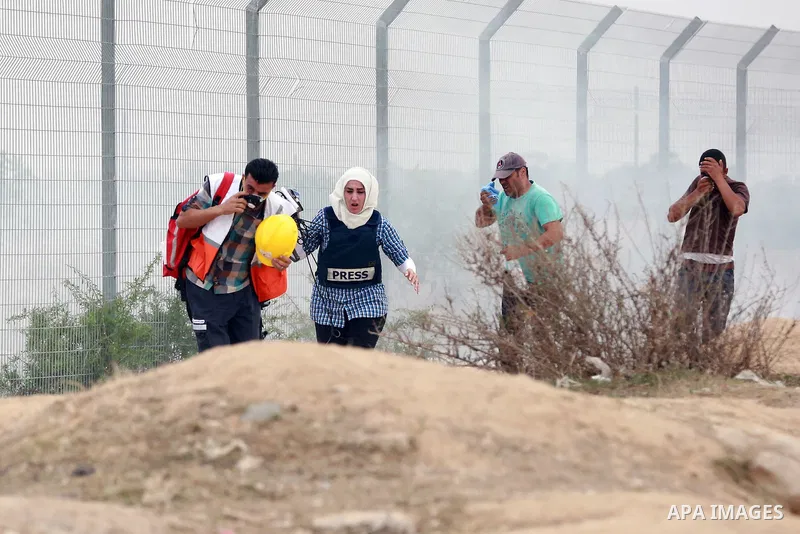 Palestinian journalists run for cover as they suffer from tear gas fired by Israeli security forces during clashes with Palestinian protesters near the border between Israeli and central Gaza Strip, on October 23, 2015....