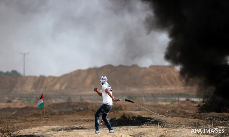 A Palestinian protester uses a sling shot to throw stones during clashes with Israeli security forces near the border between Israeli and central Gaza Strip, on October 23, 2015. Palestinian factions called for mass rall...