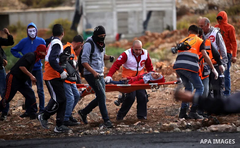Palestinian medics carry an injured protesters during clashes with Israeli security forces near the Jewish settlement of Beit El, near the West Bank city of Ramallah October 27, 2015. The current round of violence began...