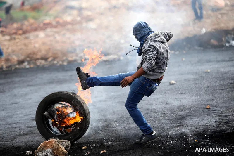 A Palestinian protester kicks a burning tire towards Israeli security forces during clashes near the Jewish settlement of Beit El, near the West Bank city of Ramallah October 27, 2015. The current round of violence began...