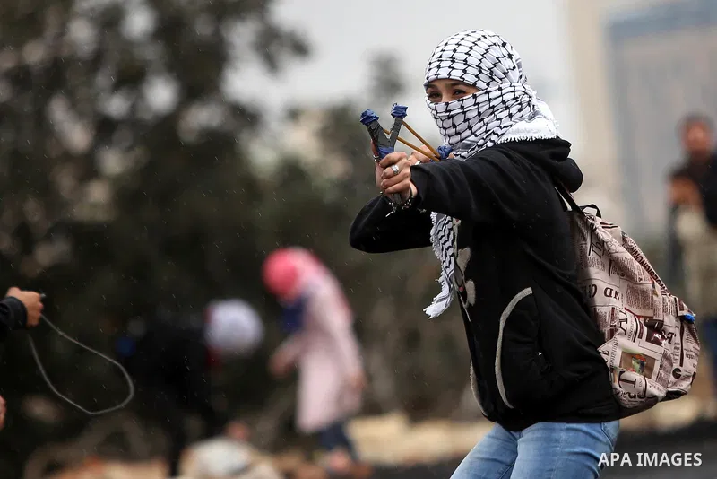 A female Palestinian protester uses a sling shot to throw stones towards Israeli security forces during clashes near the Jewish settlement of Beit El, near the West Bank city of Ramallah October 27, 2015. The current rou...