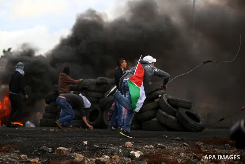 A masked Palestinian protester uses a sling shot to throw stones towards Israeli security forces during clashes near the Jewish settlement of Beit El, near the West Bank city of Ramallah October 27, 2015. The current rou...