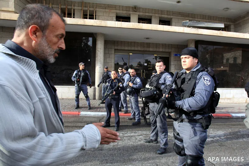 A Palestinian man walks past Israeli policemen outside a Jerusalem court, where is lader of the radical northern wing of the Islamic Movement in Israel, Sheikh Raed Salah was convicted on October 27, 2015. An Israeli cou...