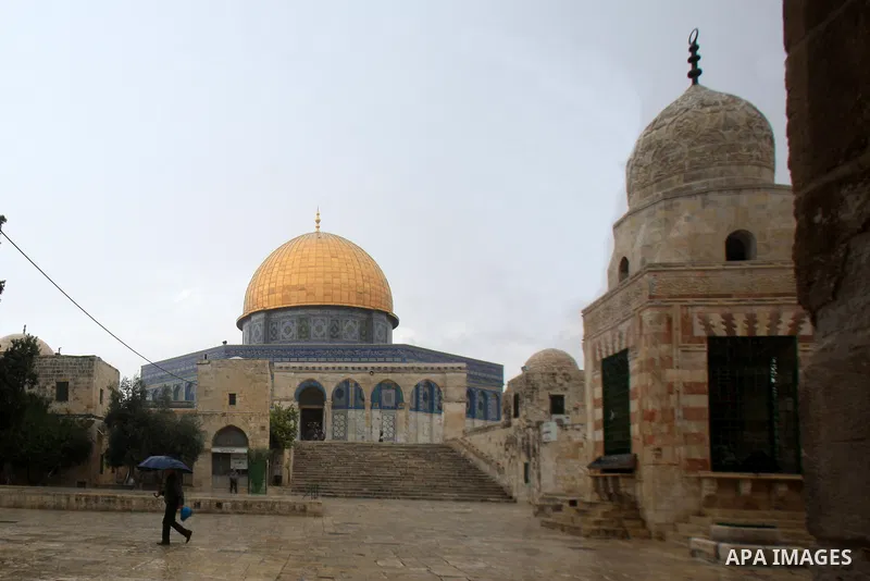 A Palestinian man holding an umbrella walks in front of the Dome of the Rock mosque, at the al-Aqsa mosque compound, in Jerusalem's Old city on October 27, 2015. Photo by Mahfouz Abu Turk