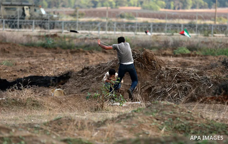 A Palestinian protester uses a sling shot to hurl stones towards Israeli troops during clashes near the border between Israel and Central Gaza Strip October 27, 2015. The current round of violence began last month with c...