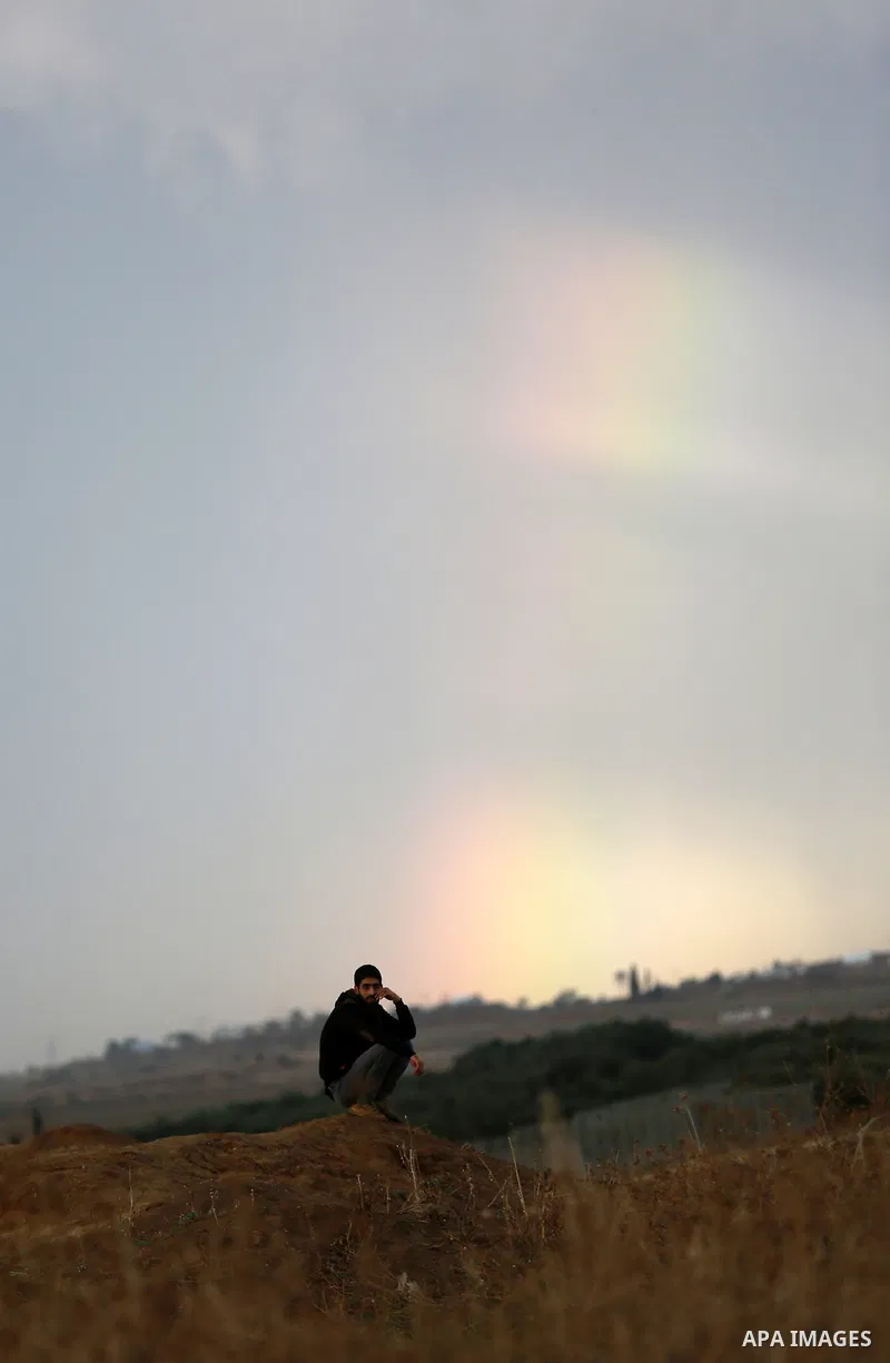 Rainbow is seen in the background as a Palestinian protester looks on during clashes with Israeli troops near the border between Israel and Central Gaza Strip October 27, 2015. The current round of violence began last mo...