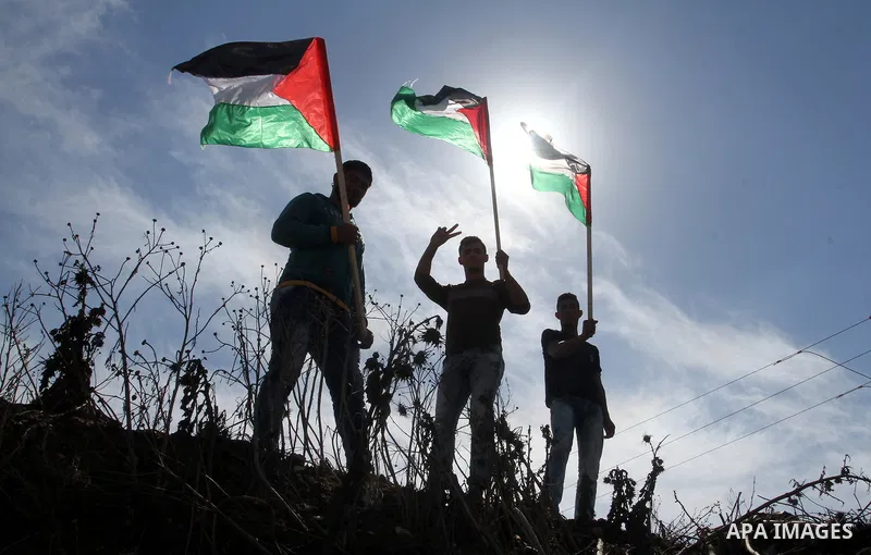 Palestinian demonstrators hold their national flag during an anti-Israel protest east of Khan Yunis, in the southern Gaza Strip, near a border fence with Israel, on October 28, 2015. Photo by Abed Rahim Khatib