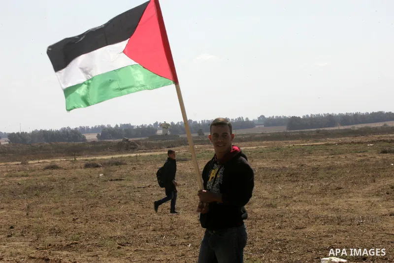 Palestinian demonstrators hold their national flag during an anti-Israel protest east of Khan Yunis, in the southern Gaza Strip, near a border fence with Israel, on October 28, 2015. Photo by Abed Rahim Khatib