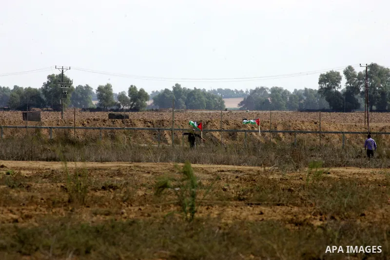 Palestinian demonstrators hold their national flag during an anti-Israel protest east of Khan Yunis, in the southern Gaza Strip, near a border fence with Israel, on October 28, 2015. Photo by Abed Rahim Khatib