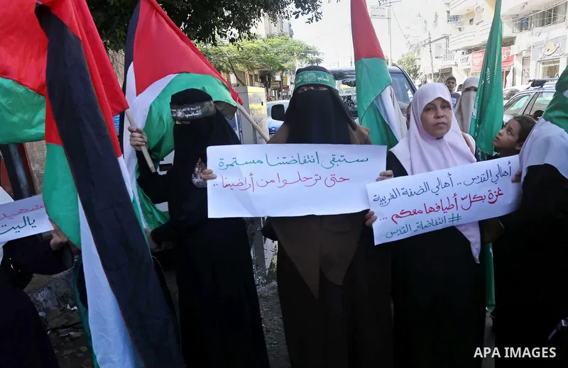 Palestinian women hold their national flag and banners during an anti-Israel protest in Gaza, on October 29, 2015. New knife attacks on Israelis in the West Bank left a soldier lightly injured, while two Palestinian assa...