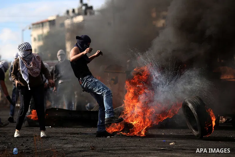 A Palestinian protester burn tires during clashes with Israeli troops near the Jewish settlement of Bet El, near the West Bank city of Ramallah, October 29, 2015. Israeli security forces shot dead two Palestinian assaila...