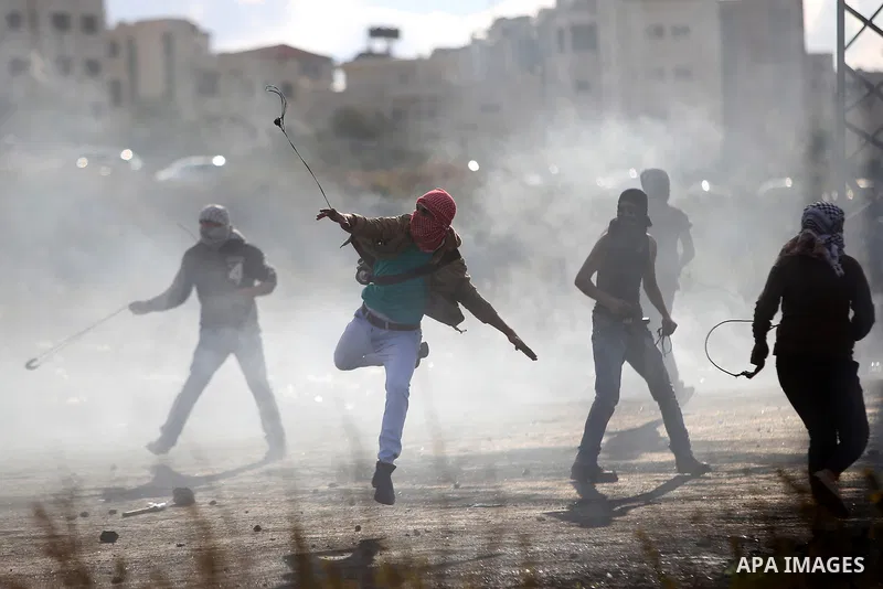 A Palestinian protester uses a sling shot to hurl stones at Israeli troops during clashes near the Jewish settlement of Bet El, near the West Bank city of Ramallah, October 29, 2015. Israeli security forces shot dead two...