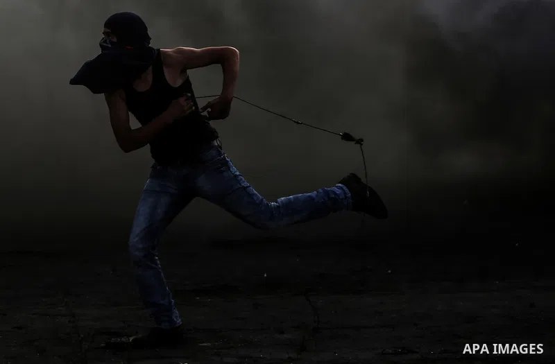 A Palestinian protester uses a sling shot to hurl stones at Israeli troops during clashes near the Jewish settlement of Bet El, near the West Bank city of Ramallah, October 29, 2015. Israeli security forces shot dead two...