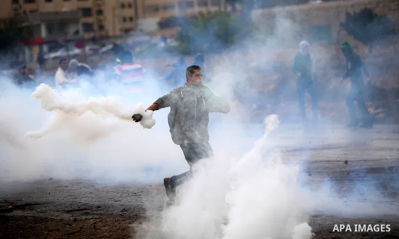 A Palestinian protester throws back a tear gas canister fired by Israeli troops during clashes near the Jewish settlement of Bet El, near the West Bank city of Ramallah, October 29, 2015. Israeli security forces shot dea...