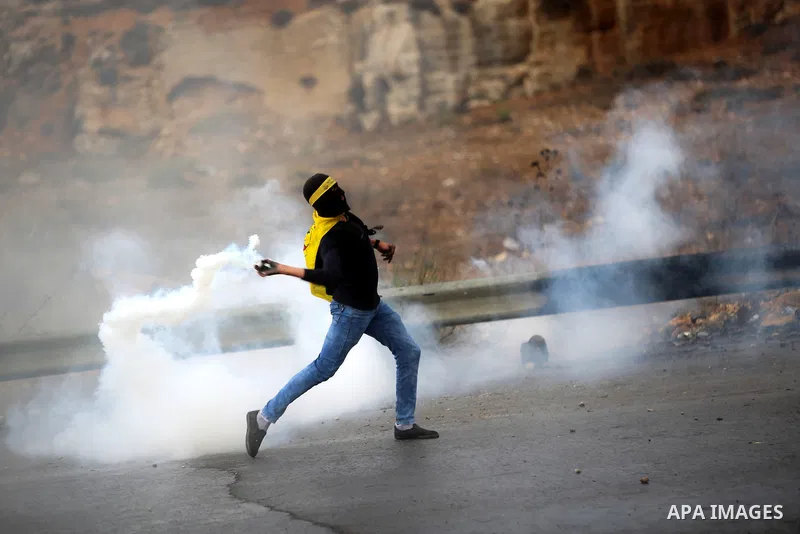 A Palestinian protester throws back a tear gas canister fired by Israeli troops during clashes near the Jewish settlement of Bet El, near the West Bank city of Ramallah, October 29, 2015. Israeli security forces shot dea...