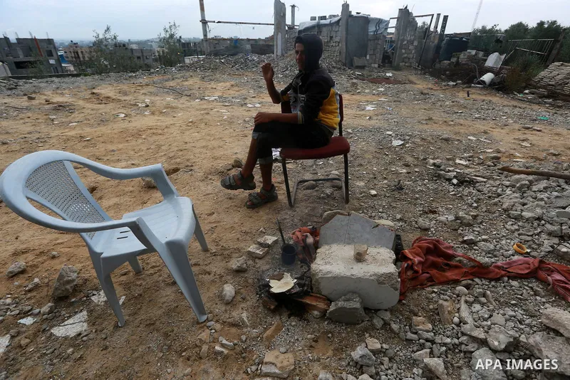 A Palestinian boy sits in front of houses which were destroyed during the 50-day Israeli war last summer, during a rainy day in Gaza city on November 9, 2015. The 50-day war in July-August 2014 killed 2,200 Palestinians,...