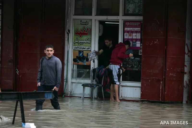 Palestinians cross a street in the town of Khan Yunis in the Gaza strip, flooded by heavy rain on November 9, 2015. Heavy rains continue to lash several parts of the Gaza Strip after the meteorological department alerted...