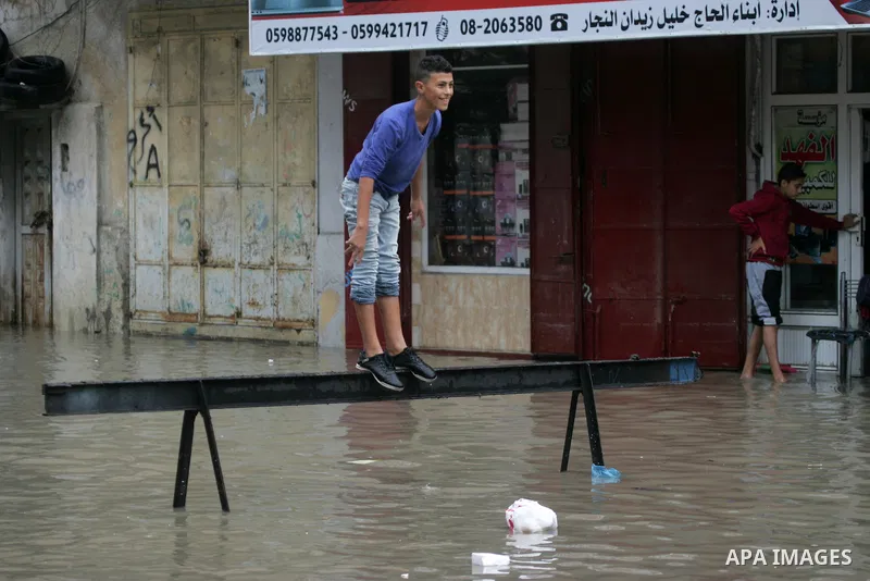 Palestinians cross a street in the town of Khan Yunis in the Gaza strip, flooded by heavy rain on November 9, 2015. Heavy rains continue to lash several parts of the Gaza Strip after the meteorological department alerted...