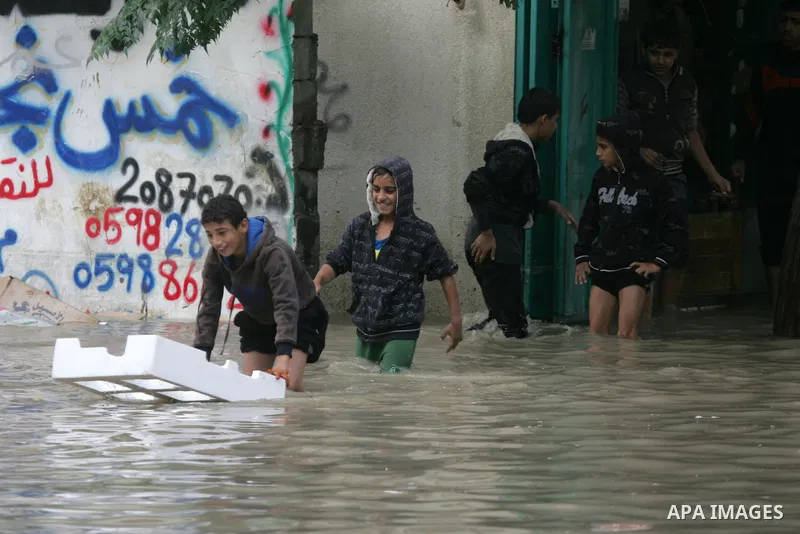 Palestinians cross a street in the town of Khan Yunis in the Gaza strip, flooded by heavy rain on November 9, 2015. Heavy rains continue to lash several parts of the Gaza Strip after the meteorological department alerted...