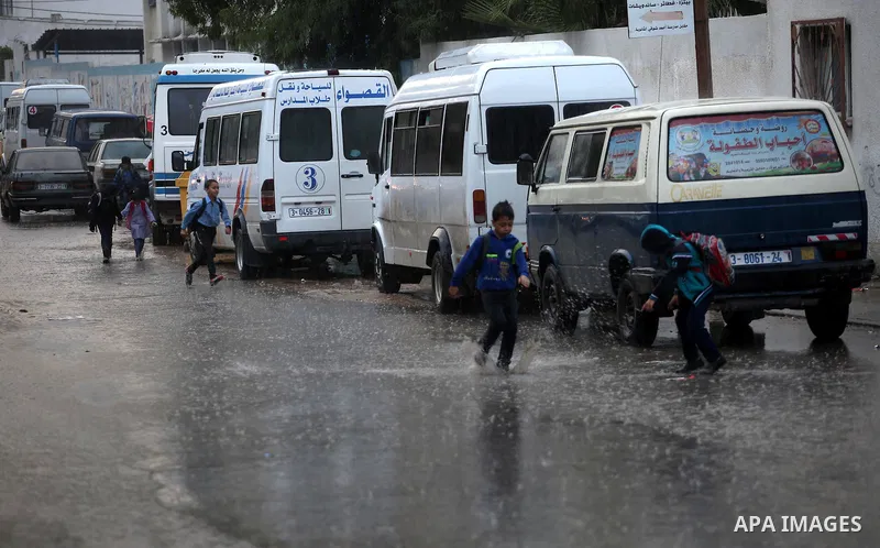 Palestinian school children walk in a street flooded by rain water in Gaza city, November 9, 2015. Heavy rains continue to lash several parts of the Gaza Strip after the meteorological department alerted a warning of hea...