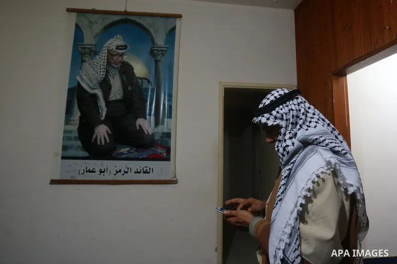 A Palestinian man stands in front of the picture of late Palestinian leader Yasser Arafat following a meeting between leaders of Hamas and Fatah movements, in Gaza city on November 10, 2011. A Fatah spokesperson said tha...