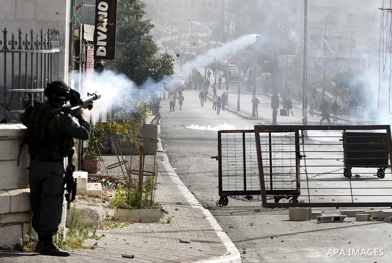 An Israeli soldier fires tear gas towards Palestinian protesters during clashes following a protest to mark the anniversary of the death of late Palestinian leader Yasser Arafat, in the West Bank city of Bethlehem, on No...