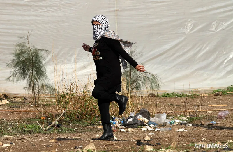 A female Palestinian protester throws stones towards Israeli security forces during clashes following a protest to mark the anniversary of the death of late Palestinian leader Yasser Arafat, in the West Bank city of Tulk...