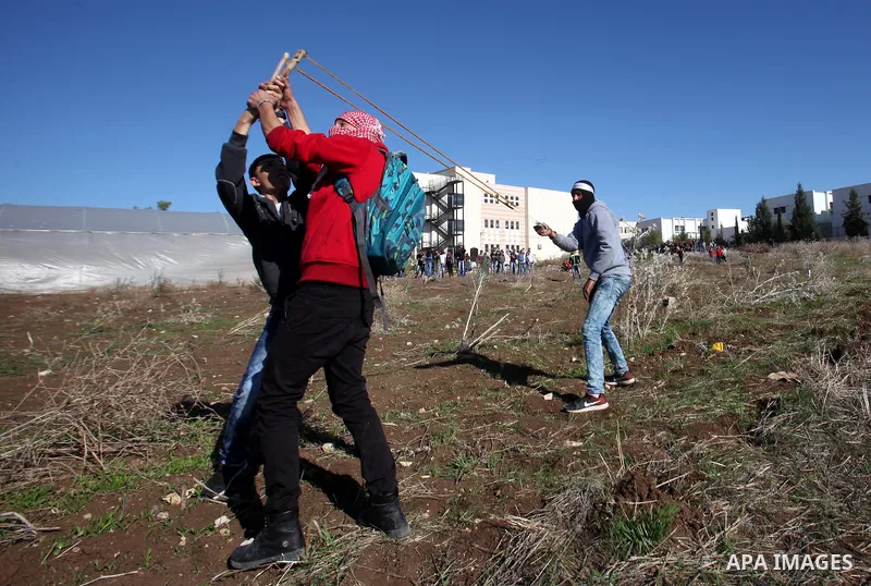 Palestinian protesters use a sling to hurl stones at Israeli troops during clashes in the West Bank city of Tulkarm November 12, 2015. Israeli undercover forces raided a hospital in the West Bank on Thursday, shooting de...