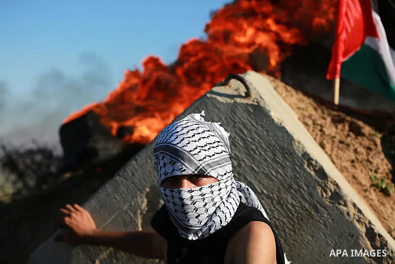 A Palestinian protester takes cover during clashes with Israeli troops near the border between Israel and central Gaza strip, November 13, 2015. The current wave of violence erupted in mid-September, fueled by rumors tha...