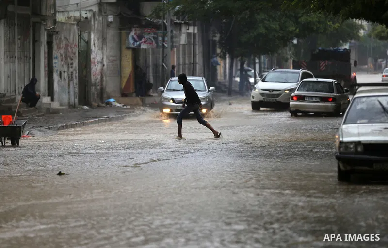 A Palestinian boy walks in a flooded street during a rainy day in Gaza city on November 17, 2015. Photo by Yasser Qudih