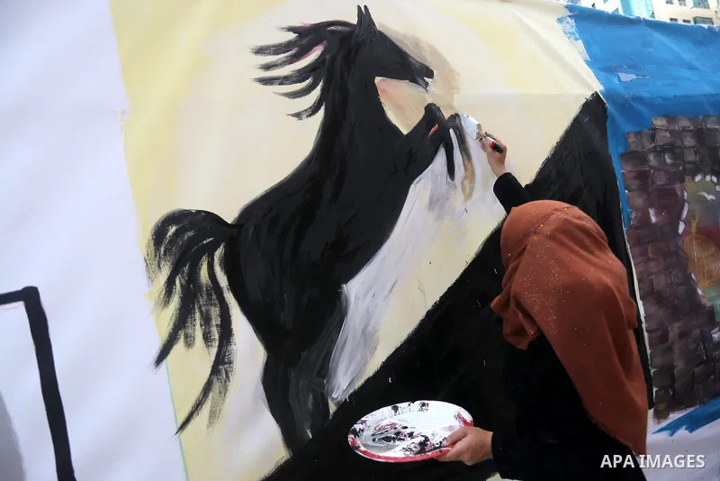 A Palestinian woman paints a mural during an event to show solidarity with the Palestinians in the West Bank and Jerusalem, in Gaza city on November 18, 2015. The surge in violence across Israel, Jerusalem and the Israel...