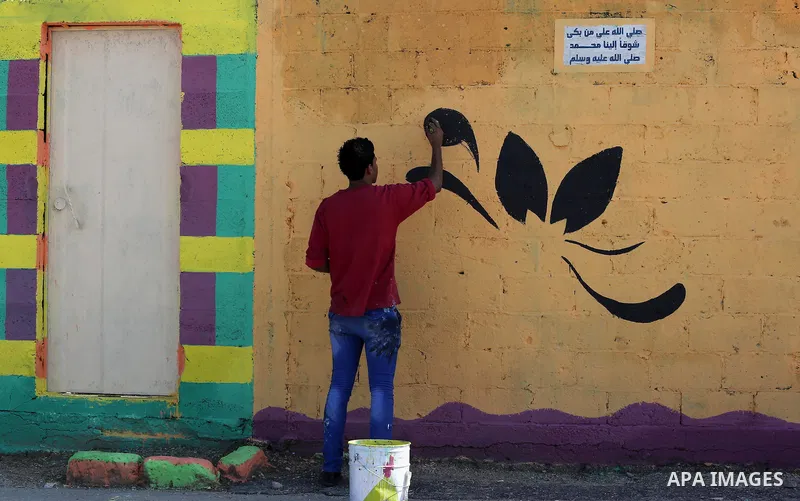 A Palestinian artist paints the facade of a house in the al-Shati refugee camp in Gaza City, on November 19, 2015, as they take part in a project with more than 30 artists funded by Padico holding, a limited public share...