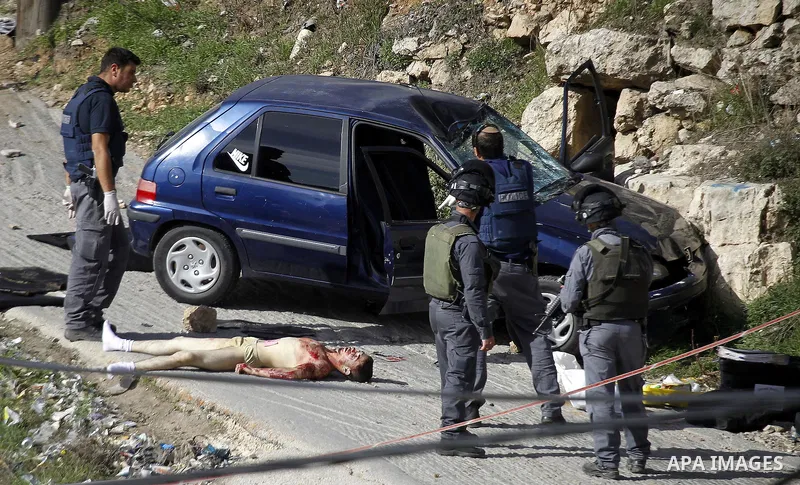 Israeli security forces inspect the body of a Palestinian man who rammed his car into Israeli soldiers injuring five of them before being shot dead, in the village of Beit Ummar, near the city of Hebron in the Israeli oc...