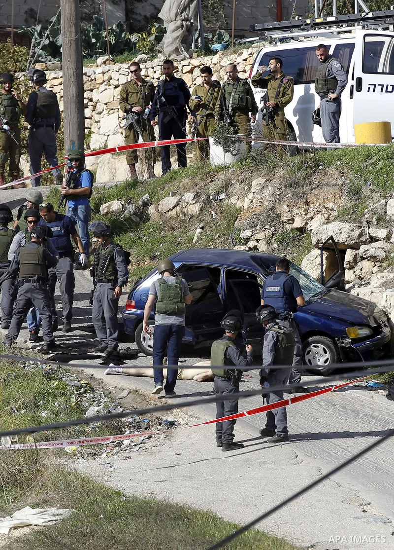Israeli security forces inspect the body of a Palestinian man who rammed his car into Israeli soldiers injuring five of them before being shot dead, in the village of Beit Ummar, near the city of Hebron in the Israeli oc...