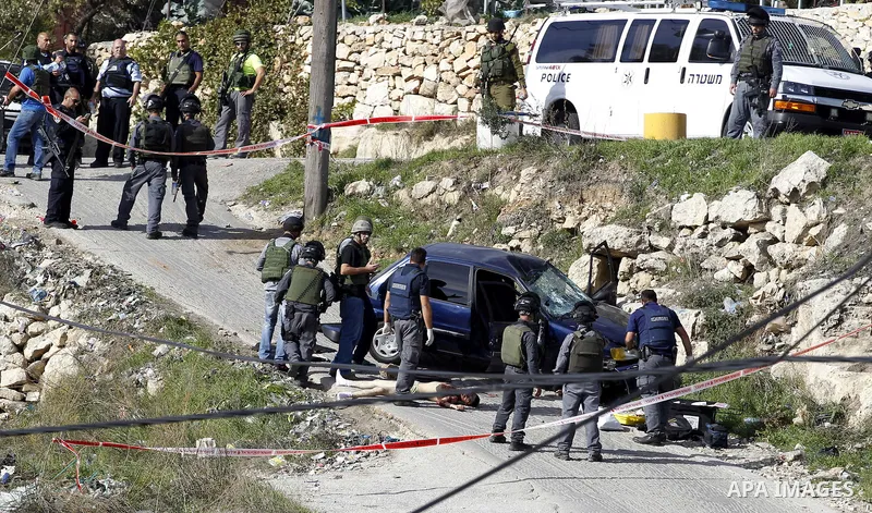 Israeli security forces inspect the body of a Palestinian man who rammed his car into Israeli soldiers injuring five of them before being shot dead, in the village of Beit Ummar, near the city of Hebron in the Israeli oc...