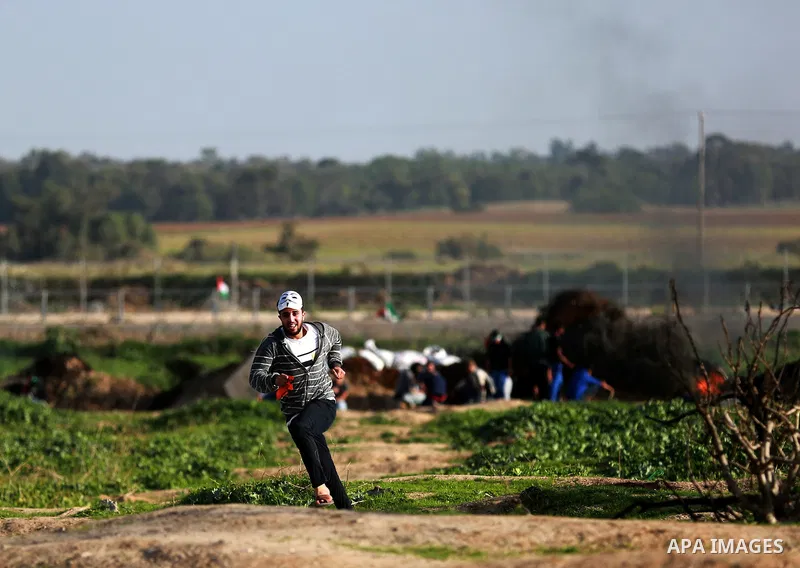 A masked Palestinian protester runs for cover during clashes with Israeli security forces near the border between Israel and the central Gaza Strip, November 27, 2015. The current wave of violence erupted in mid-Septembe...
