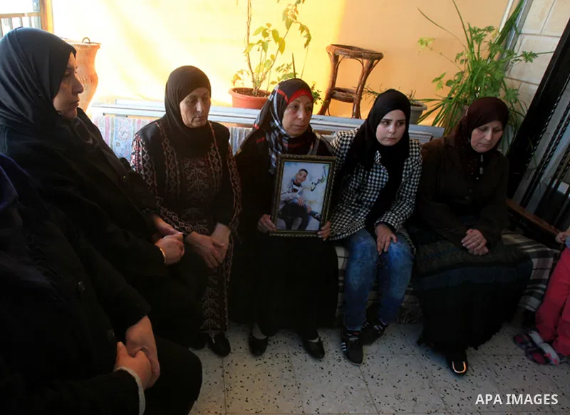 The mother of Ayman al-Abbasi, mourns as she holds her son's picture at her house in Ras al-Amoud neighborhood, in Jerusalem on November 30, 2015. A 17-year-old Palestinian youth, Ayman Al-Abbassi, was was shot with a li...