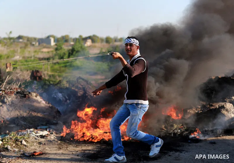 A Palestinian protester uses a slingshot to hurl stones towards Israeli security forces during clashes along the border with Israel in the eastern suburbs of Gaza City on December 4, 2015. Israeli troops shot and injured...