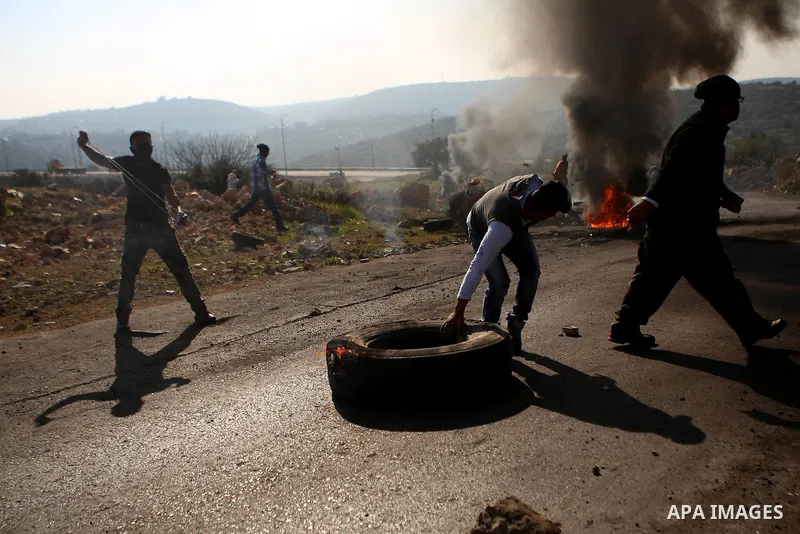 A Palestinian protester burns tires during clashes between Palestinian youth and Israeli army on December 11, 2015 in the occupied West Bank village of Silwad, northeast of Ramallah after a demonstration to call for the...