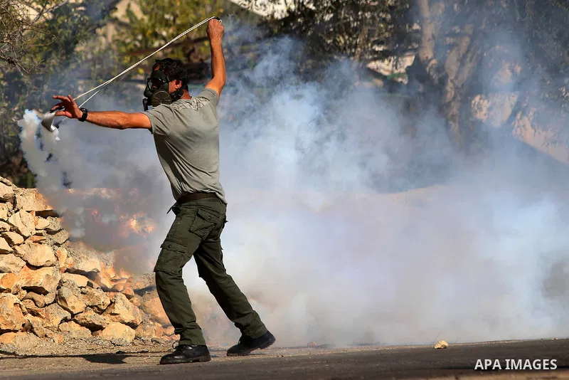 A Palestinian protester uses a slingshot to throw stones during clashes between Palestinian youth and Israeli army on December 11, 2015 in the occupied West Bank village of Silwad, northeast of Ramallah after a demonstra...