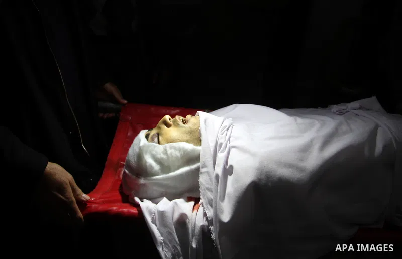 Mourners gather around the body of Palestinian Mahmoud Al-Aga, 20, whom medics said was killed by Israeli troops during clashes with Palestinian protesters on Friday, during his funeral in Khan Younis in the southern of...