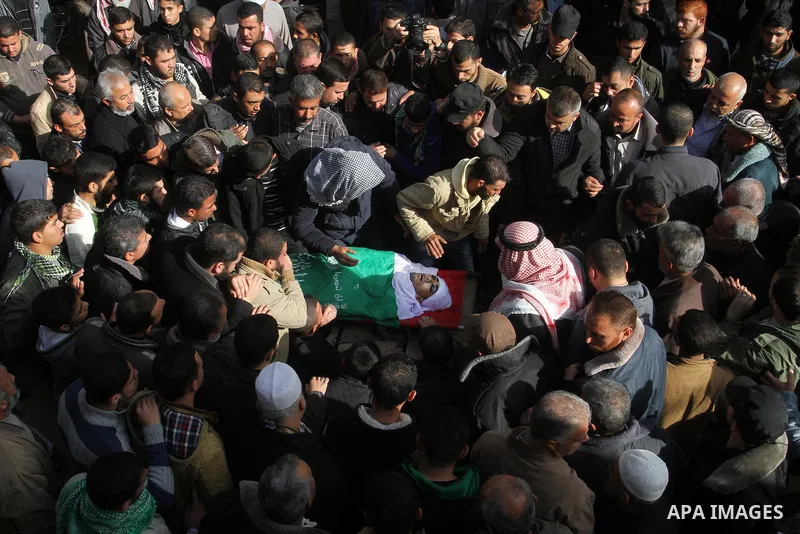 Mourners gather around the body of Palestinian Mahmoud Al-Aga, 20, whom medics said was killed by Israeli troops during clashes with Palestinian protesters on Friday, during his funeral in Khan Younis in the southern of...