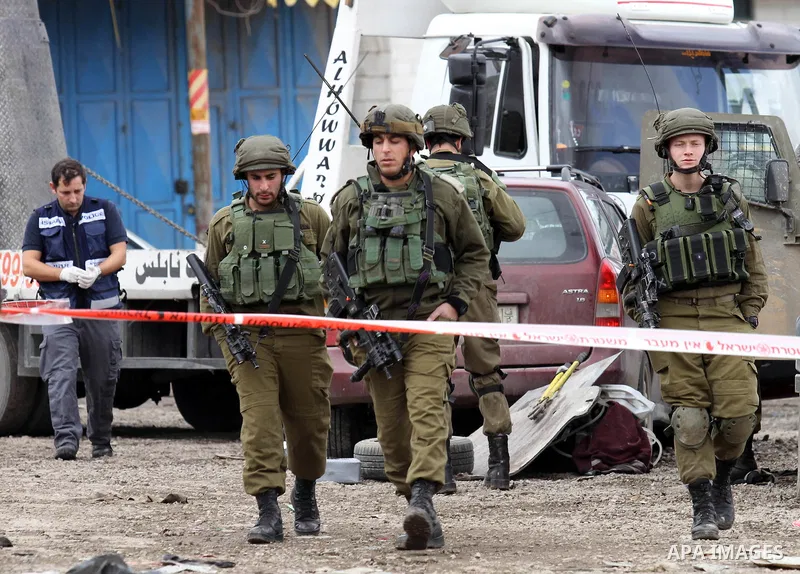 Israeli security forces gather at the site of a car ramming attack in the village of Hawara near the West Bank city of Nablus, on December 31, 2015. A Palestinian drove his car into Israeli forces before being shot dead,...