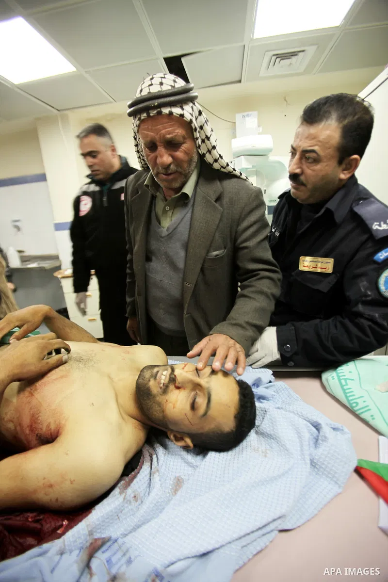 A Palestinian man grieves over his relative's body who drove his car into Israeli forces in the village of Hawara near the West Bank city of Nablus before being shot dead earlier in the day on December 31, 2015. Photo by...