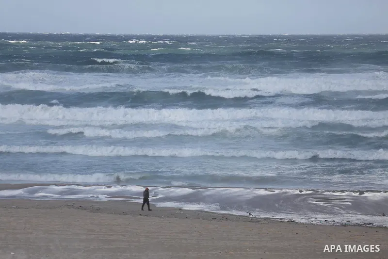 A Palestinian walks past the beach of Gaza city as waves crash fishermen's harbor on the first day of the new year on Jan. 01, 2016. Photo by Mohammed Asad