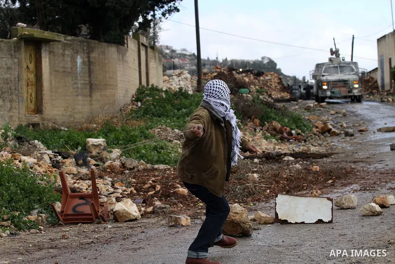 A Palestinian protester uses a slingshot to hurl stones toward Israeli security forces during clashes following a protest against the expropriation of Palestinian land by Israel in the West Bank village of Kafr Qaddum, n...