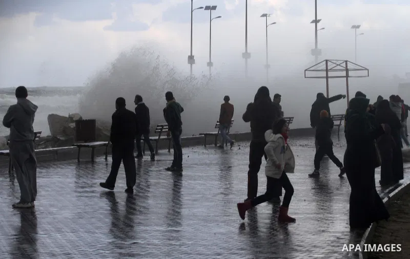 Palestinians stand in front of beach of Gaza city as waves crash fishermen's harbor during a rainy day on the first day of the new year on Jan. 01, 2016. Photo by Mohammed Asad