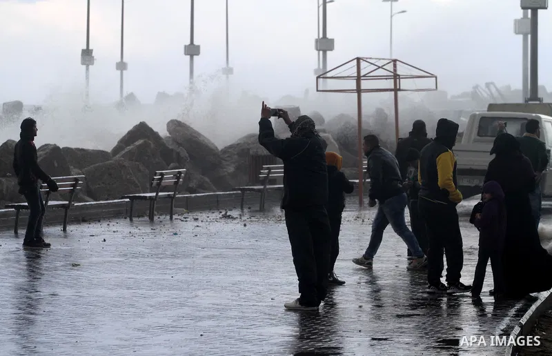 Palestinians stand in front of beach of Gaza city as waves crash fishermen's harbor during a rainy day on the first day of the new year on Jan. 01, 2016. Photo by Mohammed Asad